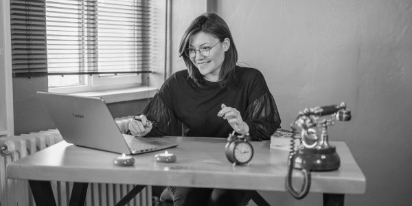A young woman working on her laptop in a vintage-style office setting.